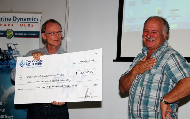 Dr Pat Garrat, uittredende Besturende Direkteur van die Twee Oseane Akwarium, oorhandig hier die tjek ten bedrae van R100,000 aan Wilfred Chivell